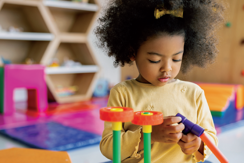 A young girl plays with a colorful toy